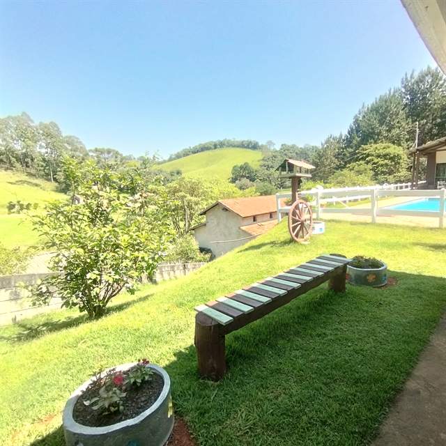 Gramado aberto com bancos de madeira e vista para as montanhas