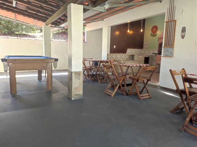 Mesa de bilhar e mesas de madeira na área coberta