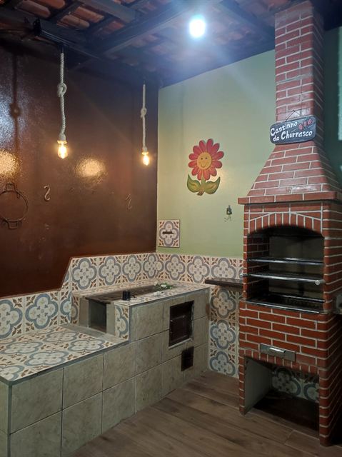 Churrasqueira de tijolo com bancada de azulejo e fogão a lenha