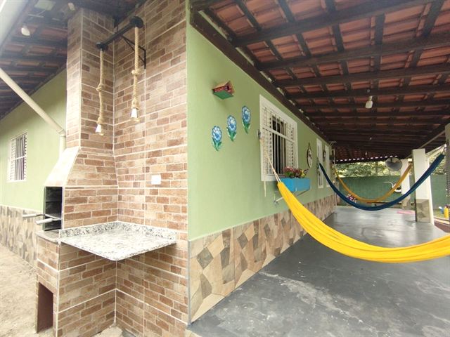 Área gourmet coberta com bancada de pedra e rede amarela