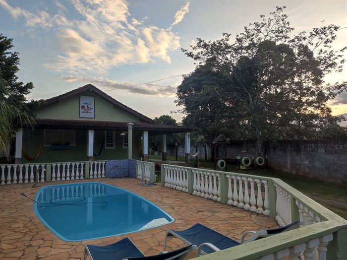 Piscina com a casa ao fundo no fim da tarde